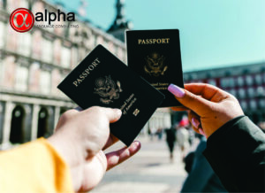 como solicitar o Green Card americano? (Na imagem tem duas mãos, cada uma segura um passaporte americano. No canto superior direito, tem a logo da Alpha Language Consulting).